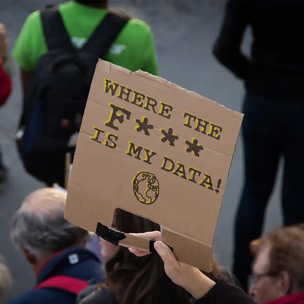 Man holding plackard saying "Where the F*** is my data."